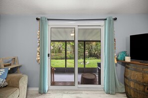 A room with a sliding glass door leading to a patio, a television on a wooden stand, and a small table with a chair. - Waterfront home on Spring, Manatees, Boat Slip, Gulf access, scalloping. (Homosassa)
