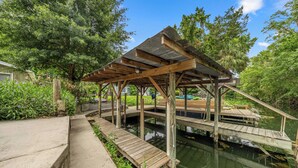 A wooden deck over water with a covered pavilion, surrounded by greenery. - Waterfront home on Spring, Manatees, Boat Slip, Gulf access, scalloping. (Homosassa)