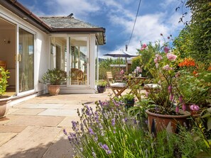 A patio with a glass door leading to a room, surrounded by potted plants and outdoor furniture. - Beautiful  villa for 5 people with WIFI and TV (Cockermouth)