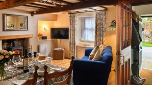 Un salon chaleureux avec un canapé bleu, des poutres en bois, une cheminée et un téléviseur.