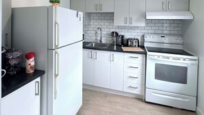 A modern kitchen with white cabinets, a refrigerator, a stove, and a sink.