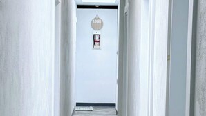 A narrow hallway with a skylight, a door with a 'LOGIS' sign, and a small rug on the floor.