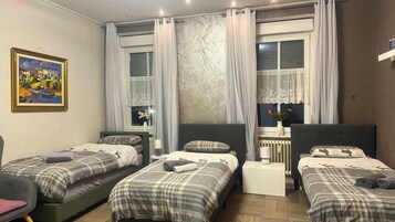 A room with two single beds, a small table, and a radiator.