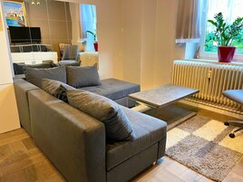 A modern living room with a grey sectional sofa, a small coffee table, and a radiator.