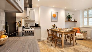 A modern kitchen with a central island, wooden chairs, and a dining table set for four.
