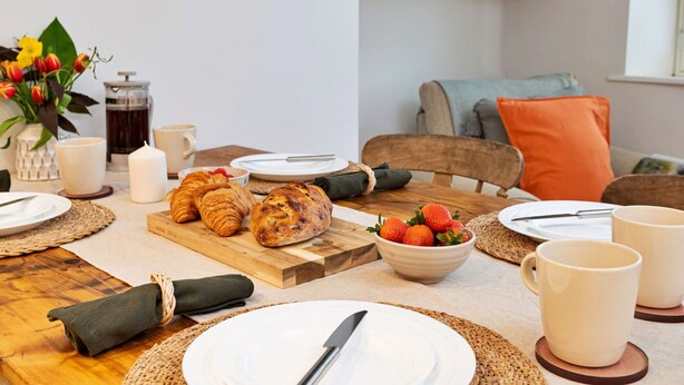 A breakfast setting with croissants, strawberries, and coffee on a wooden table.