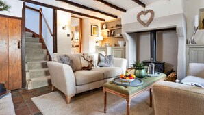 Una sala de estar acogedora con un sofá, una mesa de centro con fruta, una chimenea y una escalera.