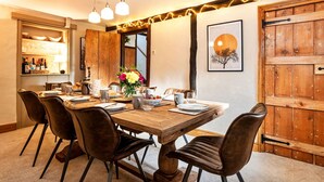 Un comedor con una mesa de madera, sillas de cuero y lámparas colgantes.