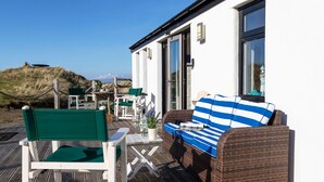 A seaside terrace with wicker furniture, a striped cushion, and a view of the beach. - Wonderful  villa for 2 people with WIFI and TV (Barrow In Furness)