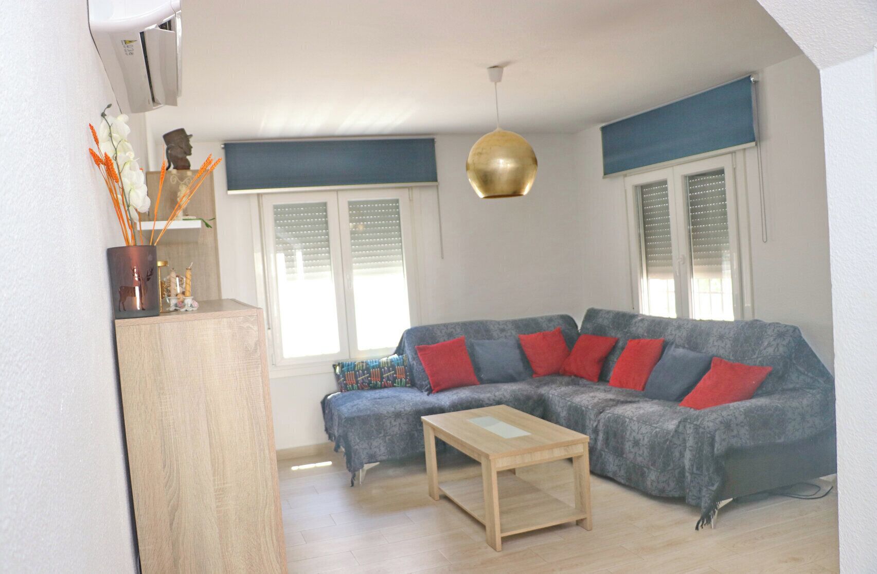 A living room with a sectional sofa, a wooden coffee table, and a hanging pendant light.