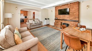 A spacious living area with a fireplace, a dining table, and a sofa. - Wonderful  villa for 4 guests with hot tub, WIFI, pool, terrace and pets allowed (Northallerton)
