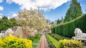 A garden pathway leading to a building with a brick facade, surrounded by manicured hedges and flowering plants. - Wonderful  villa for 4 guests with hot tub, WIFI, pool, terrace and pets allowed (Northallerton)
