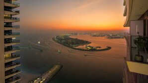 A high-rise hotel overlooking a coastal cityscape at sunset with a view of the water and distant city lights. - FIRST CLASS | 2BR | Sea & Palm View | Beachfront (Dubai)