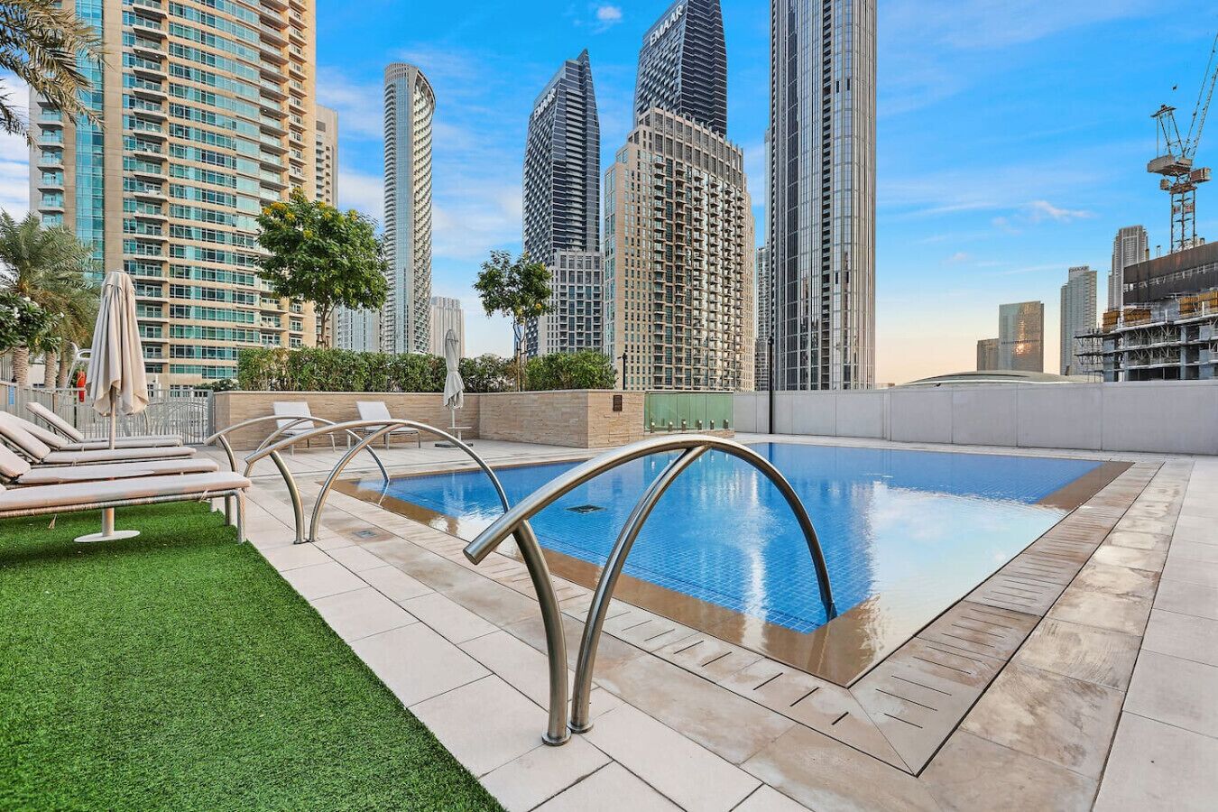A rooftop pool with lounge chairs and a view of high-rise buildings.
