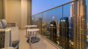 A balcony with a city view, two small tables, and a sofa.