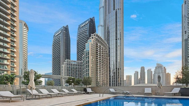 A rooftop pool with lounge chairs and a view of high-rise buildings.