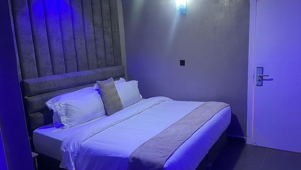 Een bed met hoofdeinde, nachtkastje en een deur.