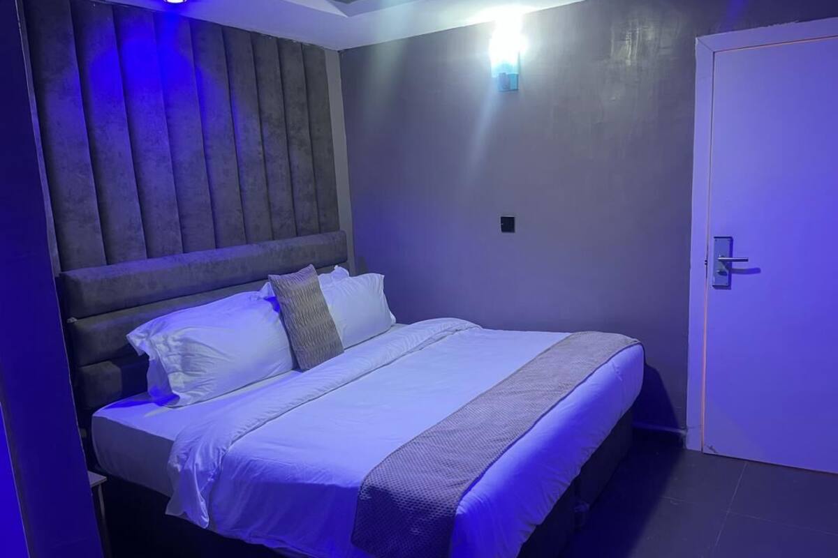 A bed with a headboard, a bedside table, and a door.