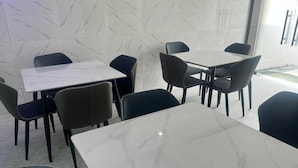 Een eethoek met marmeren tafels en zwarte stoelen.