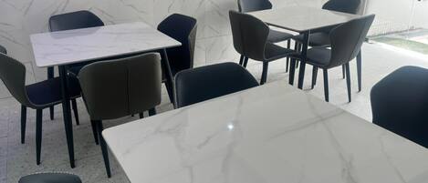 A dining area with marble tables and black chairs.