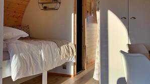 Um quarto aconchegante com teto de madeira, uma cama, um guarda-roupa e uma cadeira.