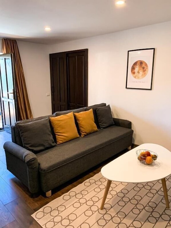 A modern living room with a dark grey sofa, yellow cushions, a white coffee table with fruit, and a framed picture on the wall. - Moon Montana Busteni (Bușteni)