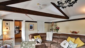 Ein gemütliches Wohnzimmer mit einem braunen Ledersofa, einer Holzbalkendecke und einer Deckenleuchte.