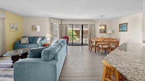 Ein Wohnzimmer mit Sofa, Couchtisch und Essbereich mit Stühlen und Tisch.