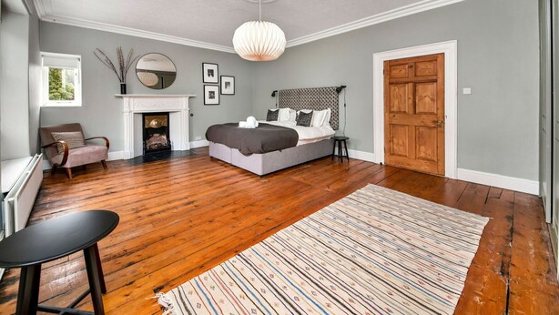 Un dormitorio con una cama grande, una chimenea, una puerta de madera y vistas al exterior.