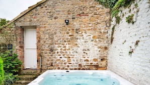 Un edificio de piedra con una puerta blanca y un jacuzzi en la parte frontal.