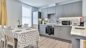 A modern kitchen with grey cabinets, a microwave, a toaster, and a dishwasher.