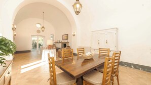 A dining area with a large wooden table, six chairs, and a chandelier.