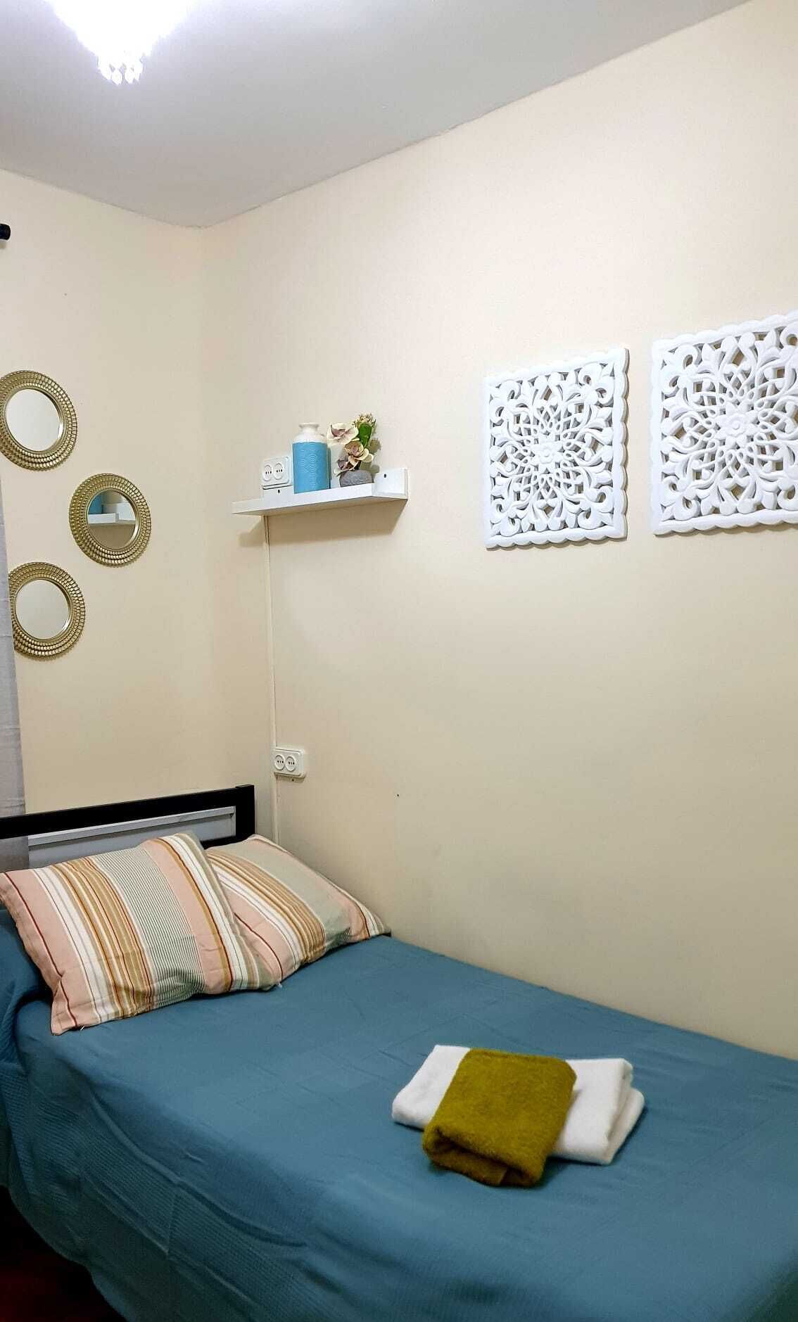 Ein Schlafzimmer mit einem Bett, Kissen, einem Regal mit Dekoration und Wandbildern.