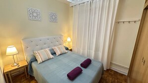 A bedroom with a bed, two nightstands, a wardrobe, and a window with curtains. - Habitaciones en Luisa (Madrid)