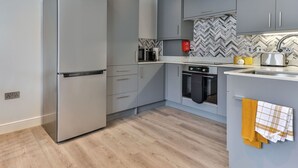 A modern kitchen with grey cabinets, a stainless steel refrigerator, a microwave, and an oven. - Nice apartment for 2 people with WIFI, TV and pets allowed (Filey)