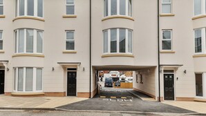 A row of townhouses with bay windows, a parking area with 'SLOW' marking, and a customer car park sign. - Nice apartment for 2 people with WIFI, TV and pets allowed (Filey)