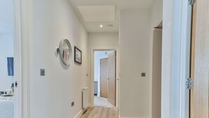 A hallway with light-colored walls and wooden flooring. There is a door on the right and a radiator on the left. - Lovely apartment for 4 people with WIFI and TV (Filey)