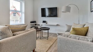 A modern living room with two grey sofas, a coffee table, a TV mounted on the wall, and a floor lamp. - Lovely apartment for 4 people with WIFI and TV (Filey)