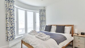 A bedroom with a bed, bedside tables, and a window with curtains. - Beautiful apartment for 4 guests with WIFI, TV and pets allowed (Filey)