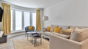 A modern living room with a sofa, armchairs, a coffee table, and a TV. - Beautiful apartment for 4 guests with WIFI, TV and pets allowed (Filey)