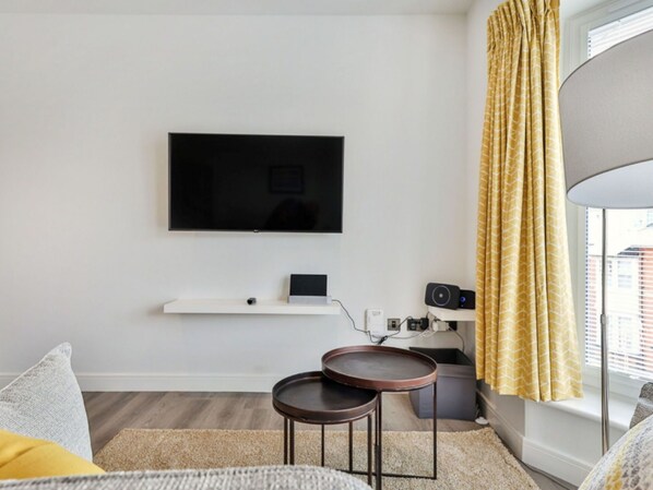 Un salon moderne avec un téléviseur à écran plat fixé au mur, une petite table et un canapé.