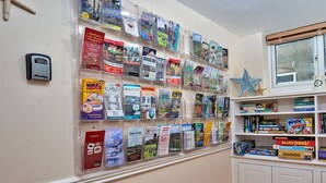 Un mur orné de divers dépliants de voyage et une petite étagère contenant des jeux de société.