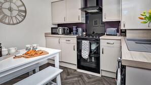Une cuisine moderne avec des meubles blancs, une cuisinière noire et une grande horloge murale.