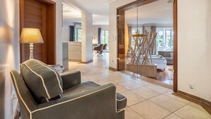A modern interior with a sofa, a lamp, a wooden door, and a view into another room. - Guest House 'Traumhaus Whirlpool Sauna Grill' with Private Terrace, Wi-Fi and Air Conditioning (Hamburg)