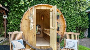 A wooden sauna with a bench and a bench seat, surrounded by greenery. - Guest House 'Traumhaus Whirlpool Sauna Grill' with Private Terrace, Wi-Fi and Air Conditioning (Hamburg)