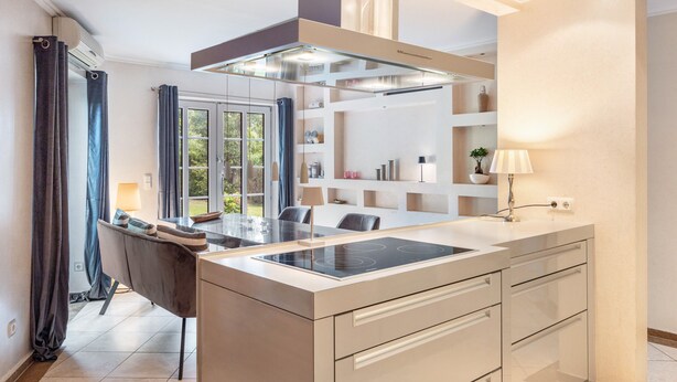 A modern kitchen with a central island, built-in shelves, and a dining area with a table and chairs. - Guest House 'Traumhaus Whirlpool Sauna Grill' with Private Terrace, Wi-Fi and Air Conditioning (Hamburg)