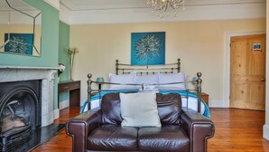 A bedroom with a bed, a chandelier, a fireplace, and a leather chair. - Stunning  villa for 10 guests with WIFI, TV and pets allowed (Whitby)