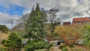 A pathway leading through a garden with various plants and trees, bordered by a stone wall and a fence. - Stunning  villa for 10 guests with WIFI, TV and pets allowed (Whitby)