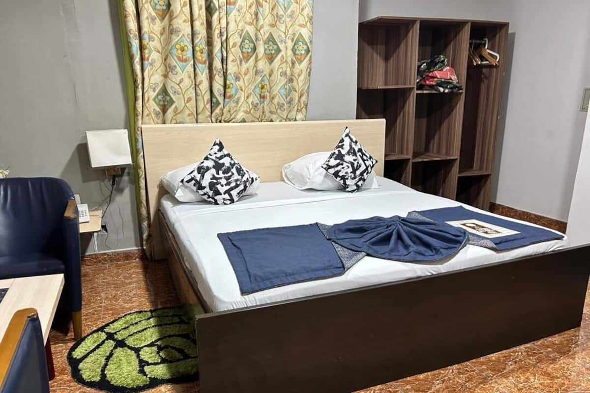 Una cama bien hecha con almohadas estampadas, una colcha azul y un cabecero de madera.