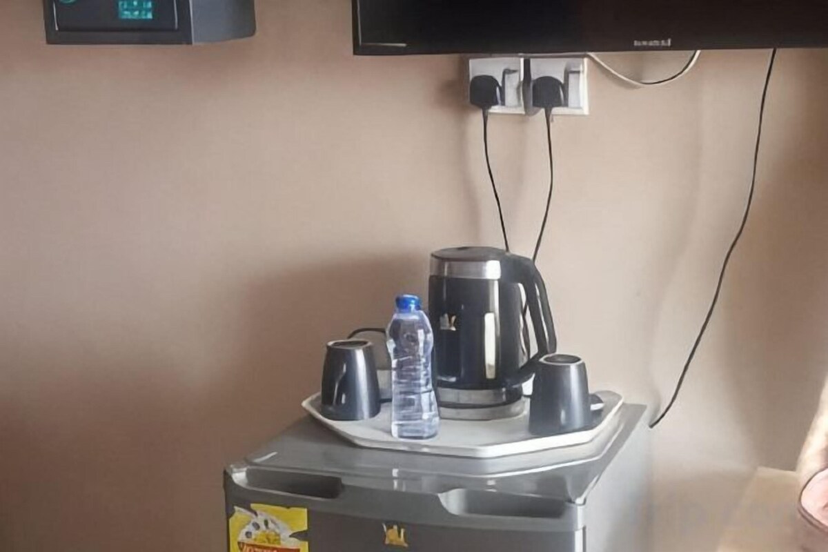 A coffee maker, a water bottle, and a cup on a table.